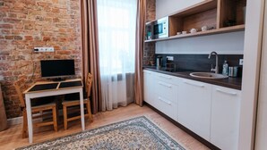 A compact kitchen with a wooden table, a TV, and a microwave. - Pernavas studio loft with free parking (Riga)