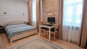 A bedroom with a bed, a desk with a computer, a chair, and a rug. - Pernavas studio loft with free parking (Riga)