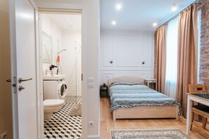 A bedroom with a bed, a nightstand, a chair, and a view of a brick wall. - Pernavas studio loft with free parking (Riga)