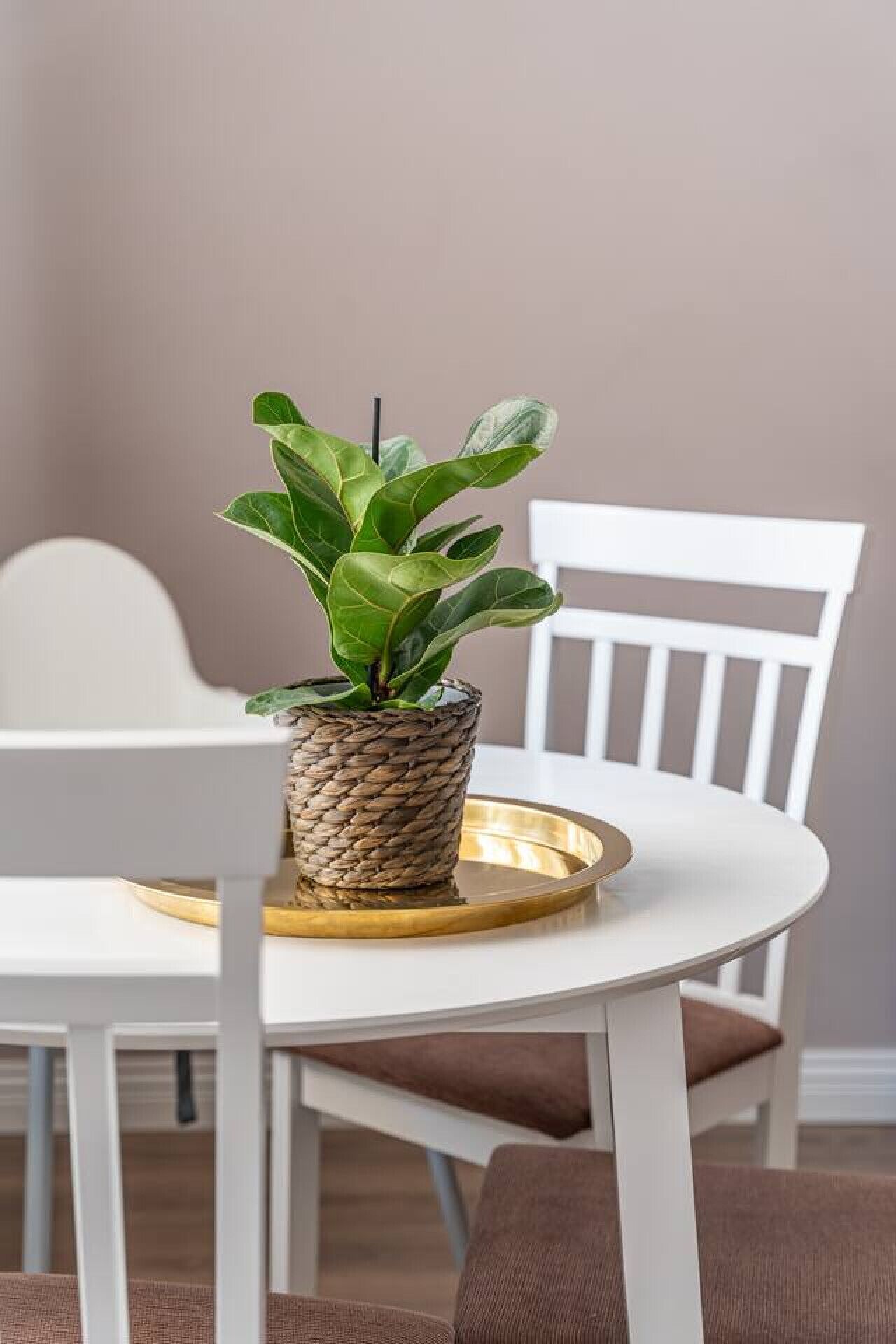 A dining table with a woven plant pot and a gold tray.