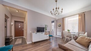 Una sala de estar moderna con sofá, televisor, mesa de comedor y candelabro.