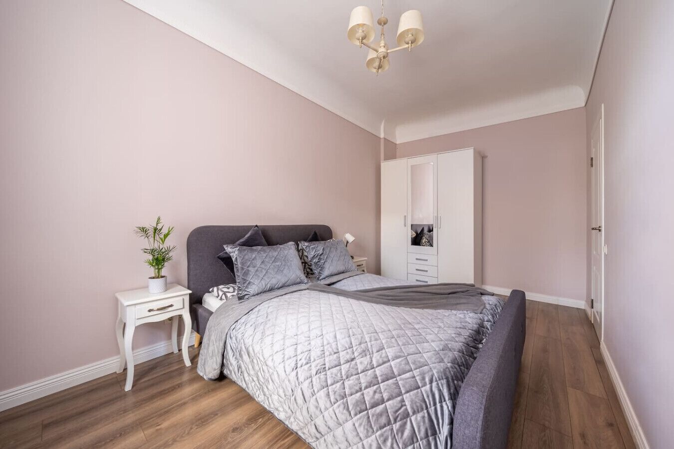 A bedroom with a bed, bedside table, nightstand, and a wardrobe.