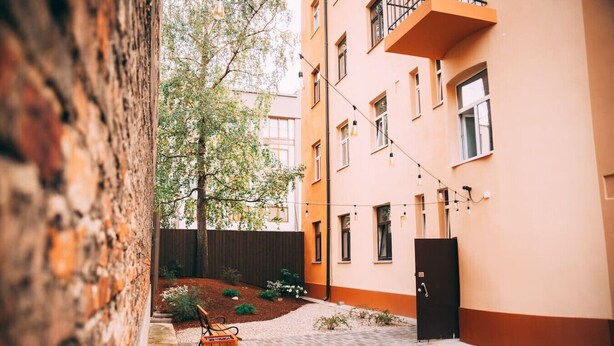 Un patio con un banco de madera, una jardinera pequeña y un edificio con balcón.