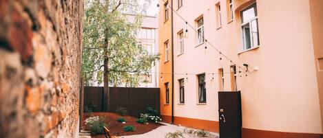 Un patio con un banco de madera, una maceta pequeña y un edificio con múltiples ventanas y balcones.
