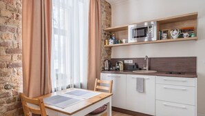 A small kitchen with a wooden table and chairs, a microwave, a kettle, and a sink.