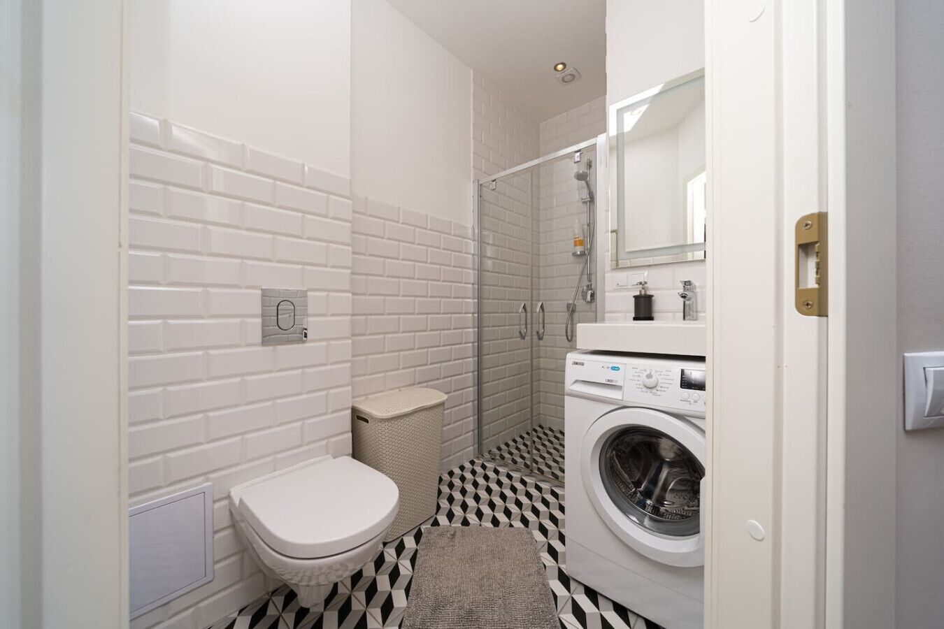 Une petite salle de bain comprenant des toilettes, un lave-linge et un espace douche.