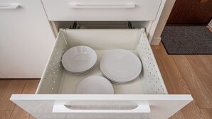 A kitchen drawer with white interior and a white exterior, containing three stacked white plates.