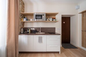 A compact kitchenette with a microwave, sink, and storage cabinets. - Fresh Studio at Pērnavas 15A | Ground Floor (Riga)
