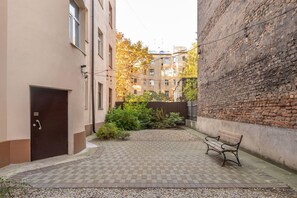 A courtyard with a bench, a door, and a brick wall. - Fresh Studio at Pērnavas 15A | Ground Floor (Riga)