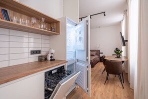 A compact kitchen with a dishwasher, a coffee machine, and a shelf with glassware. - TOP location New high class furnishing 32 m2 (Riga)