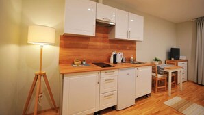 A compact kitchenette with a wooden countertop, white cabinets, a small sink, and a dining area with a table and chairs. - Hanzas residence near ArtNouveau quarter & OldTown (Riga)