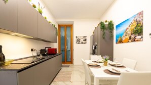Una cocina moderna con comedor, un hervidor rojo y una puerta que da a otra habitación.