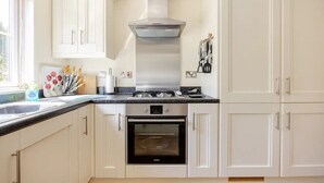 A kitchen with white cabinets, a stainless steel range hood, a built-in oven, and a window with blinds. - Luxury lodge in peaceful surroundings (saltaash)