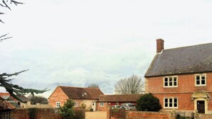 Une maison traditionnelle en briques, avec une allée en gravier et une petite pelouse.