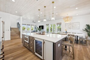 A spacious kitchen with a large island, wooden flooring, and pendant lighting.