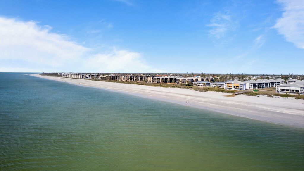 A coastal hotel with a long beachfront, multiple buildings, and a clear view of the ocean.