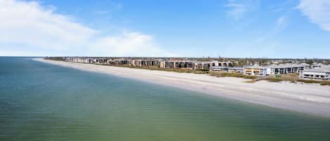 A coastal hotel with a long beachfront, multiple buildings, and a clear view of the ocean.