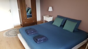 Ein Schlafzimmer mit einem Bett, einem Holzschrank, einem Nachttisch mit Lampe und einem gemusterten Teppich.