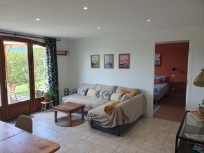 Un salon comprenant un canapé, une table basse, une table à manger et donnant sur l’extérieur.