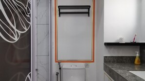 A modern bathroom with a toilet, a shower, and a sink.