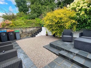 A patio with outdoor furniture, a stone wall, and a variety of plants.