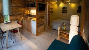 A cozy cabin-style room with a wooden interior, a kitchenette, a dining area, and a bed. - Charming Chalet in Sint Maartenszee (Sint Maartensvlotbrug)