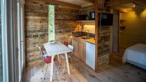 A compact cabin with a kitchenette, a dining area, and a bedroom. - Charming Chalet in Sint Maartenszee (Sint Maartensvlotbrug)