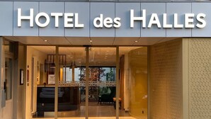 The entrance of HOTEL des HALLES with a modern design, featuring a glass door and a visible interior with seating and decor. - Hôtel des Halles (Dijon)
