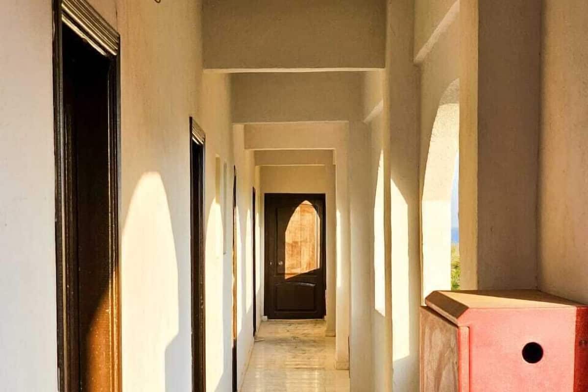 A corridor with a tiled floor, a red object on the right, and a door at the end.