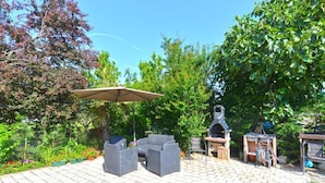 En udendørs patio med grill, siddeområde og en pergola.