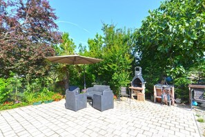 An outdoor patio with a grill, seating area, and a pergola. - Charming Coastal Gateway (Fazana)