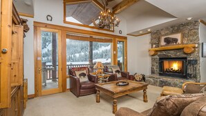 A cozy living room with a fireplace, leather sofas, and a large window overlooking a snowy landscape. - 2BR Ski-In/Ski-Out Condo, Private & Quiet, Steps to Lone Moose Lift – Big Sky (Big Sky)