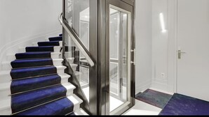A staircase with blue carpeted steps leading to a glass door. - Maison Labruyère (Bordeaux)