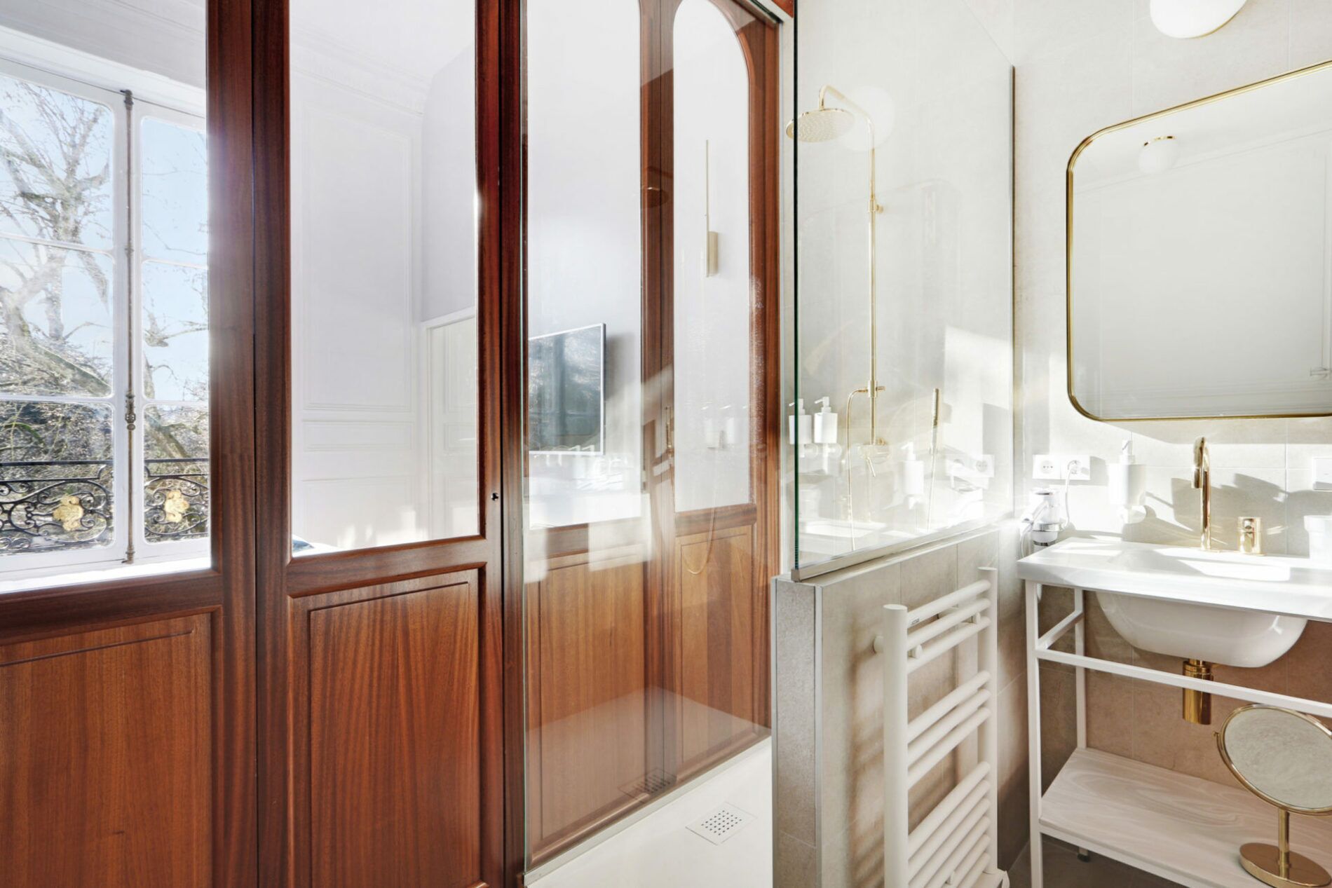 Een moderne badkamer met een douchecabine van glas, een witte wastafel en een grote spiegel.