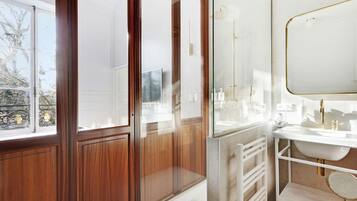 Een moderne badkamer met een douchecabine van glas, een witte wastafel en een grote spiegel.