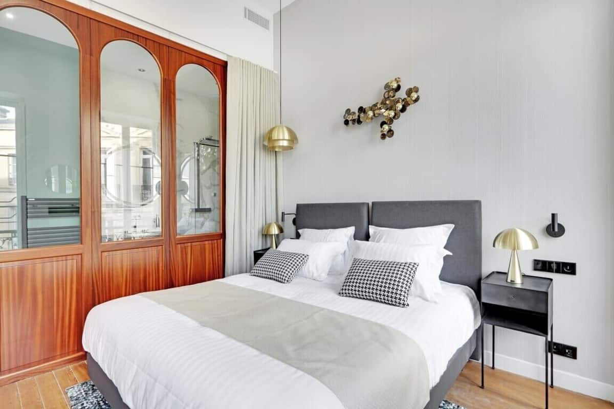 A modern bedroom with a large bed, wooden wardrobe, and a decorative wall piece.