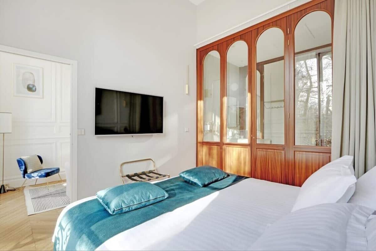 A bedroom with a bed, a television, a wardrobe, and a window.