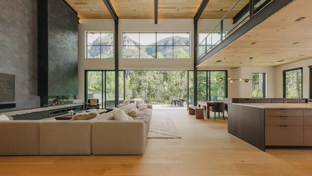 A spacious living area with a large sofa, a fireplace, and a kitchen area with a large island.
