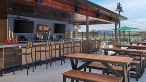 Un espace bar extérieur avec un comptoir, des sièges et une enseigne indiquant « OUTPOST BAR ».