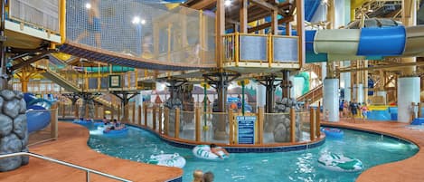 An indoor water park with a pool, slides, and play structures.