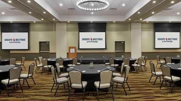 Una sala conferenze con diversi tavoli e sedie, dotata di schermi che mostrano 'GROUPS MEETINGS' e 'Grand Sierra'.