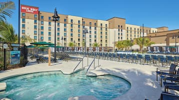 Zona de piscina de un hotel con sillas de descanso, un letrero de Great Wolf Lodge y un cartel de prohibición de clavados.