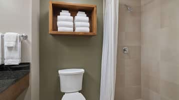 A bathroom with a toilet, a shower with a curtain, and a wooden shelf with towels.