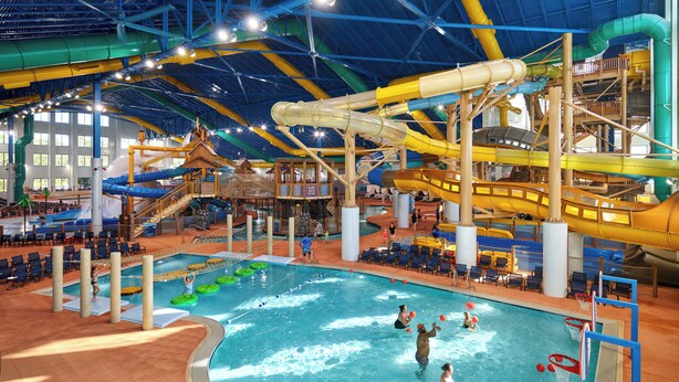 Un parc aquatique intérieur doté d’une grande piscine, de toboggans et de diverses structures de jeux.