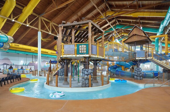 An indoor water park with a central pool, slides, and a wooden play structure. - Great Wolf Lodge Webster (Webster)