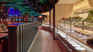 A buffet area with a variety of food items, a long counter with seating, and decorative ceiling lights. - Great Wolf Lodge Webster (Webster)