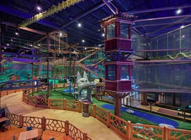 Zona de juegos interior con estructuras de escalada, toboganes y una gran escultura de hielo.