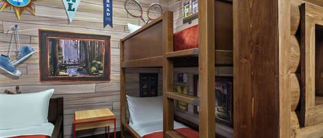 A cozy room with bunk beds, a small table, and a framed picture on the wall.