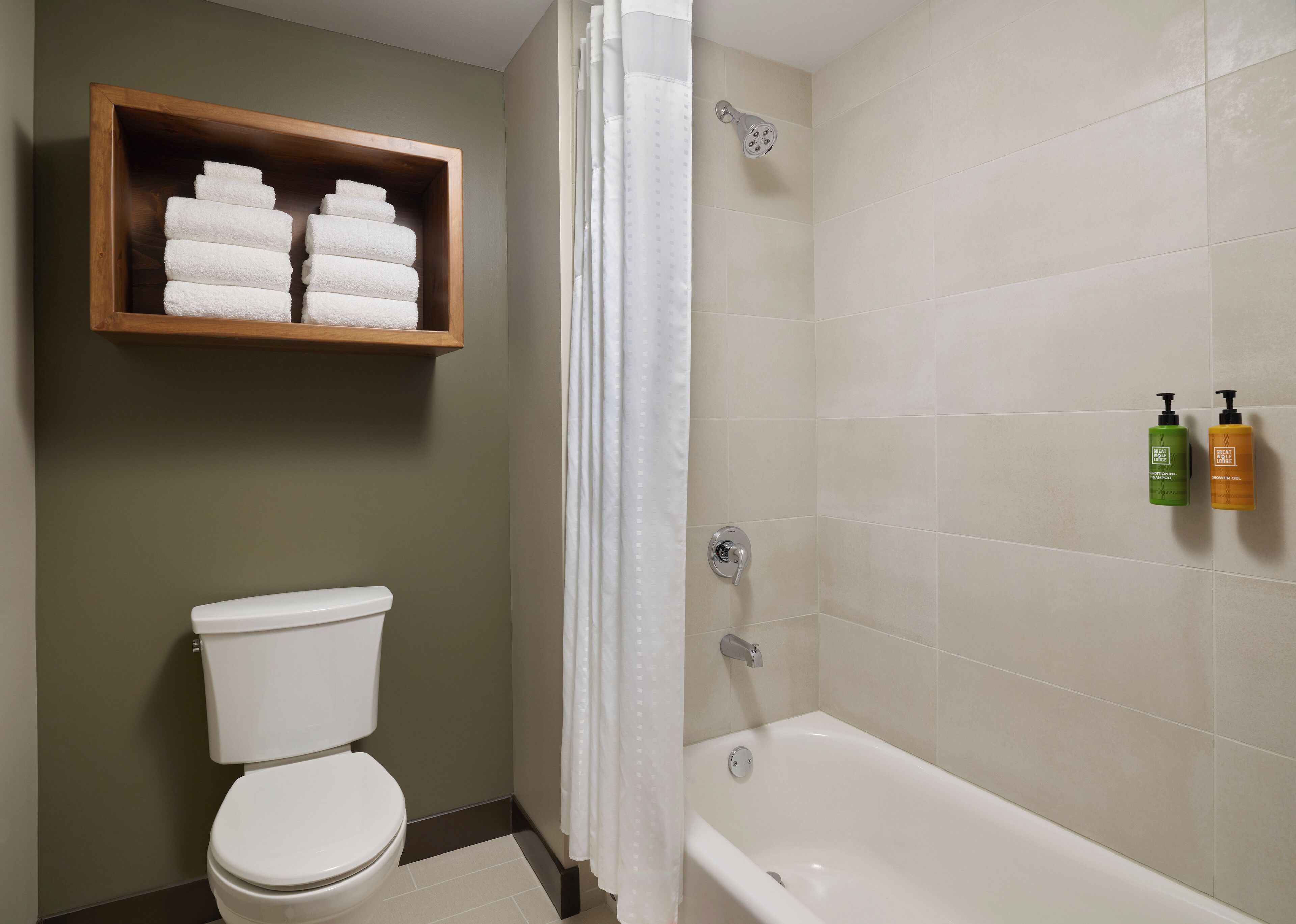 Een badkamer met toilet, douche en een plank met opgevouwen handdoeken.
