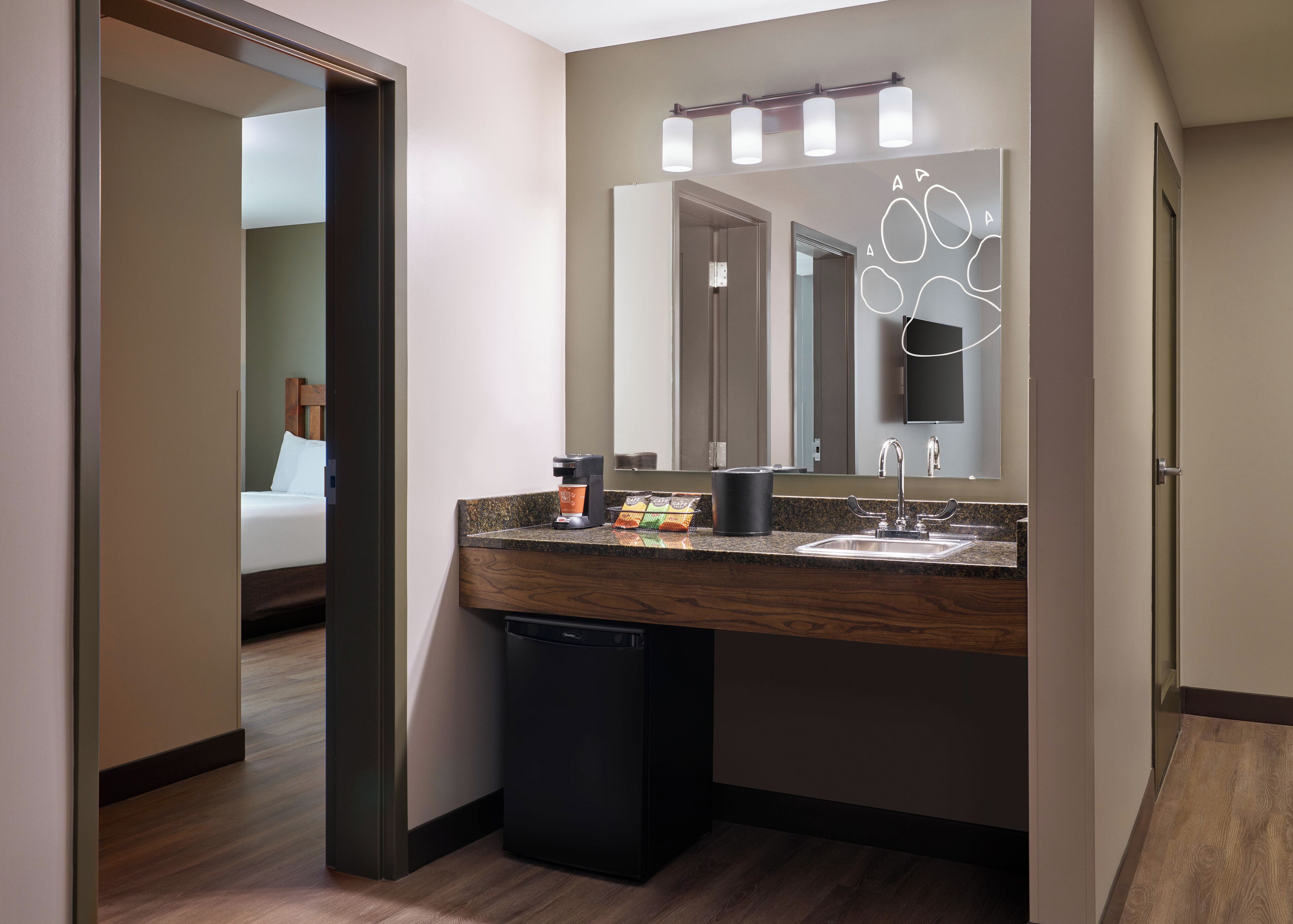 Un baño moderno con tocador de madera, un lavamanos, un espejo con iluminación y un cubo de basura.